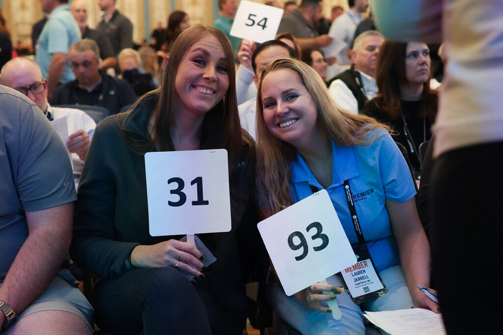 Ashley Emerson and Lauren Jarrell from Premier Rental-Purchase raising paddles to place orders during the HOT Show.