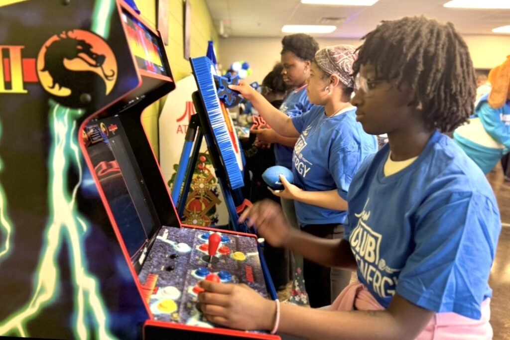 Several teenagers face video arcade machines, immersed in their game-playing.