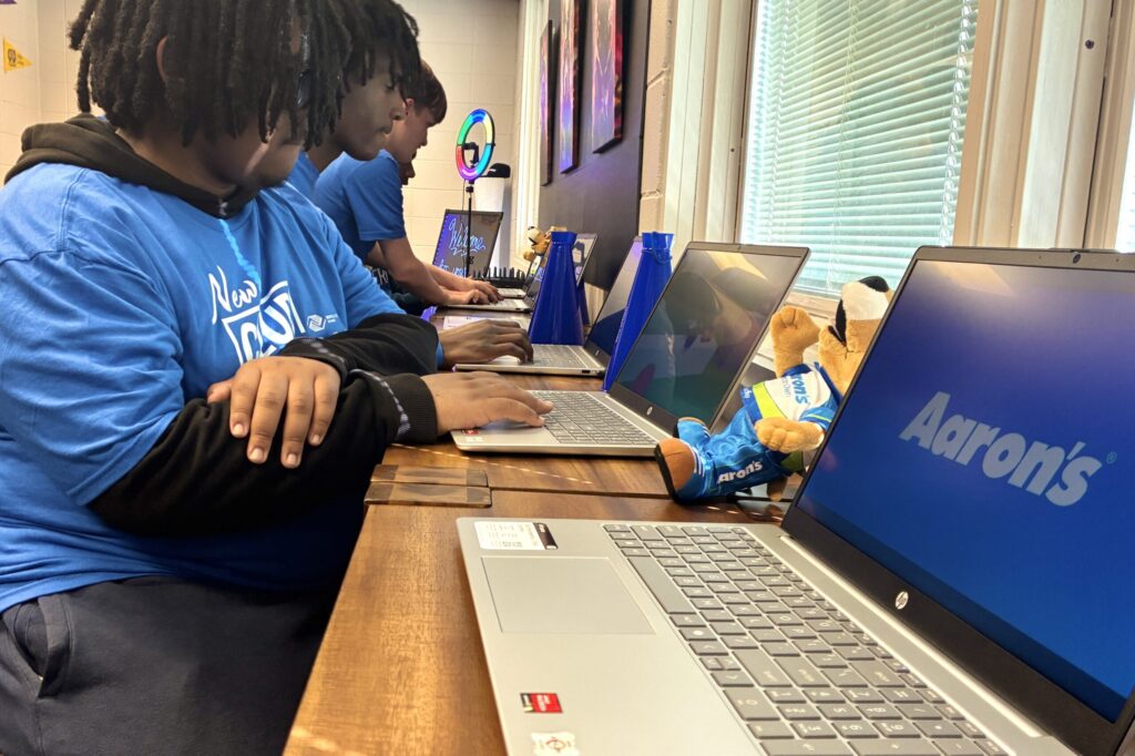 A line of teenagers sitting and busily engaged at laptops.