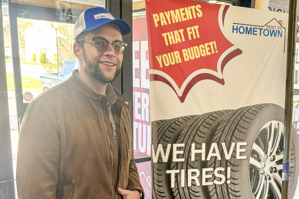 J.P. Bryant stands next to a standing banner promoting tire rental.
