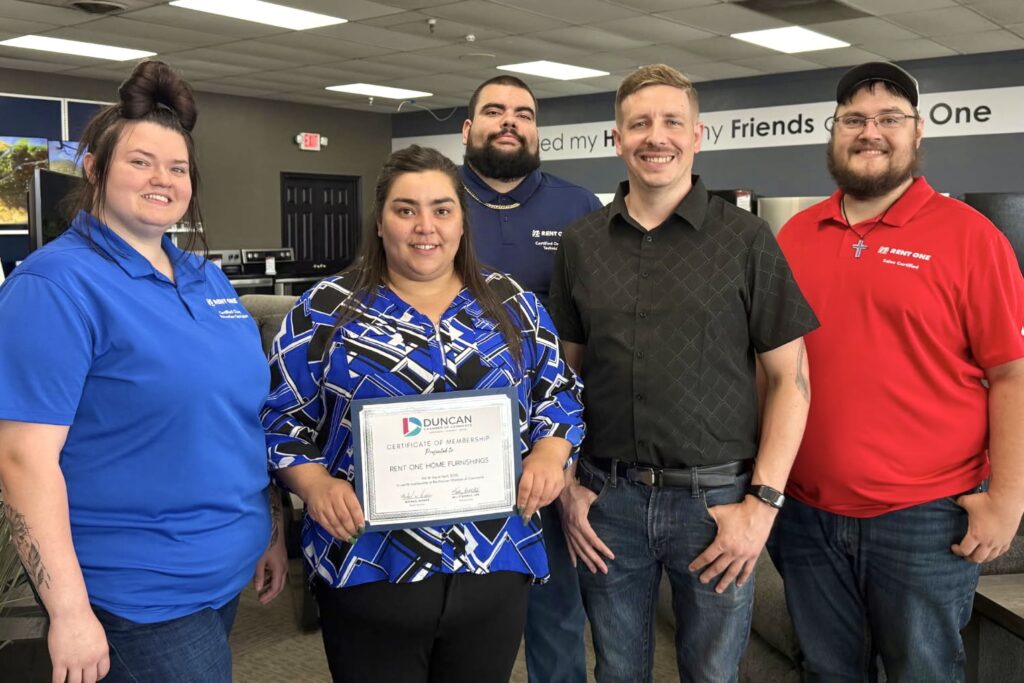 A small group of Rent One employees stand smiling with Pamela Horn at the center, who holds a Duncan, Oklahoma, Chamber of Commerce membership certificate. 