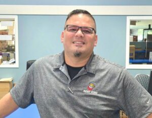 Man with glasses wearing a grey shirt that displays the text "Rent King"