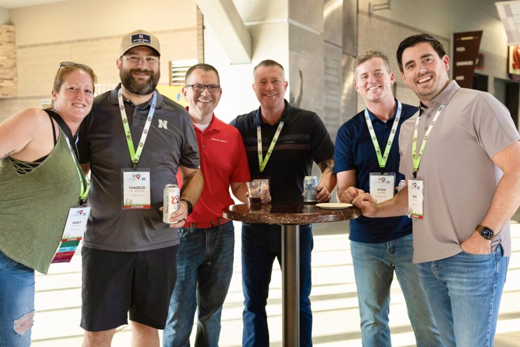 Several people stand together, smiling and holding drinks.