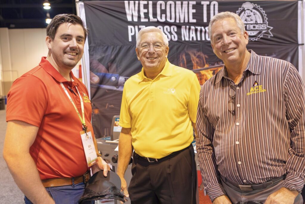 Three men standing next to each other smiling.