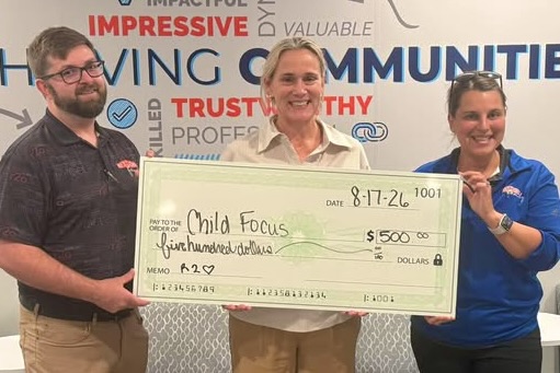 Three people stand smiling and holding up an oversized check for $500 from R2O to Child Focus.